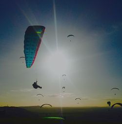 Low angle view of people paragliding against sky