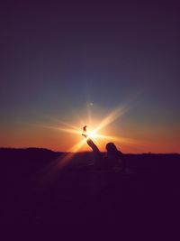 Silhouette people on land against sky during sunset