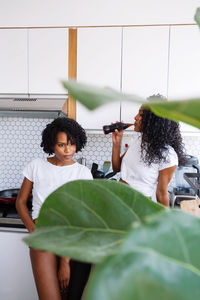 Two black women drinking coca cola in their kitchen