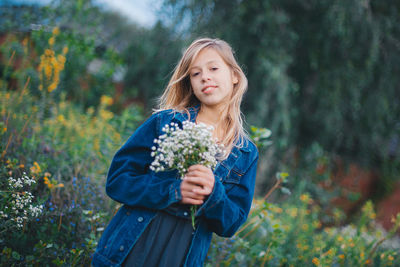 Portrait of young woman standing against plants