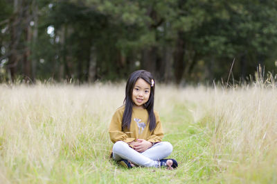 Portrait of young woman sitting on field
