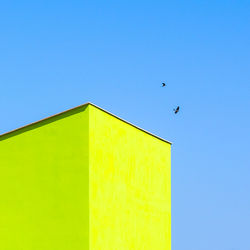 Low angle view of bird flying against clear blue sky