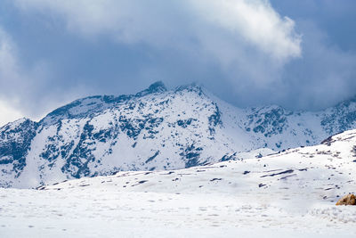 Snow cap mountains with dark cloudy sky at day from flat angle