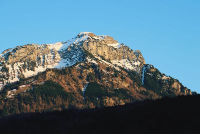 Low angle view of mountains against clear blue sky during winter