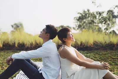 Rear view of couple sitting on field