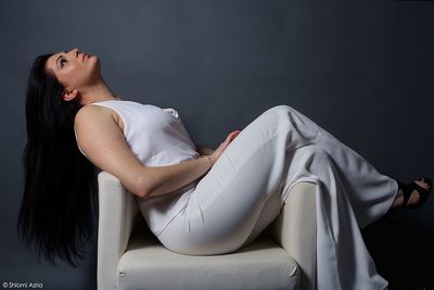Midsection of woman sitting against black background