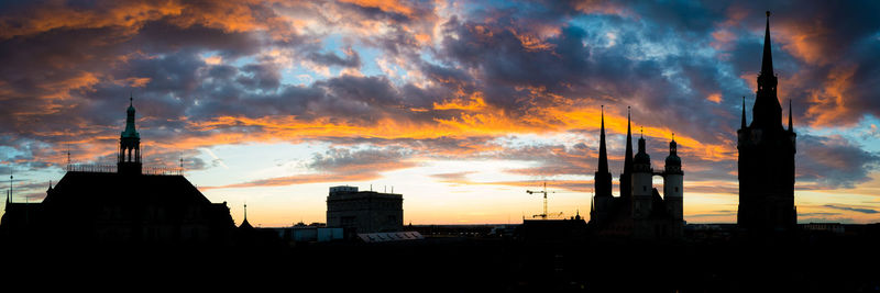 Silhouette buildings against dramatic sky during sunset