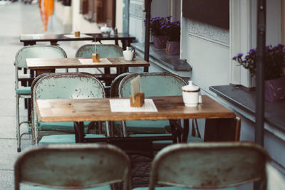 Empty chairs and tables at sidewalk cafe