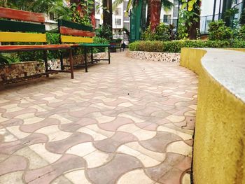 Empty footpath amidst buildings in city on sunny day