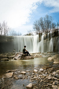 Man surfing in waterfall against sky