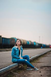 Portrait of young woman sitting against blue sky