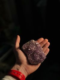 Close-up of woman hand holding leaf against black background