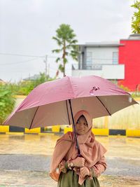 Portrait of woman holding umbrella during rainy season