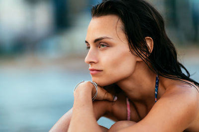 Close-up of beautiful young woman looking away at beach