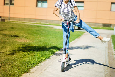 Low section of woman riding electric push scooter outdoors