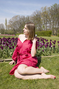 A young beautiful girl in a red dress in spring park plays with her hair,flirts