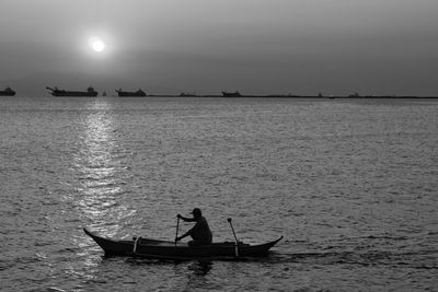 Silhouette people in boat in sea