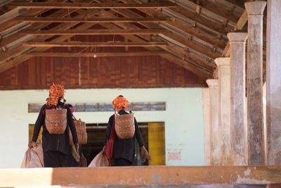 Rear view of women carrying baskets in building