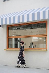 Side view of woman standing against building