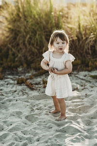 Full length of 2 year-old girl standing at beach during sunset