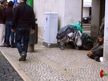 People on footpath by street in city