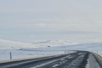 Road leading towards snowcapped mountains against sky