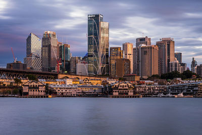 Illuminated buildings by river against sky at night