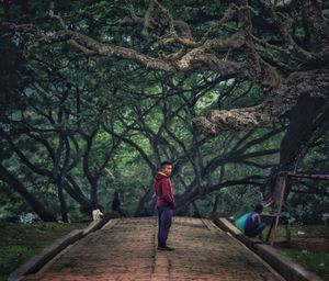 Teenage boy standing on footpath against trees