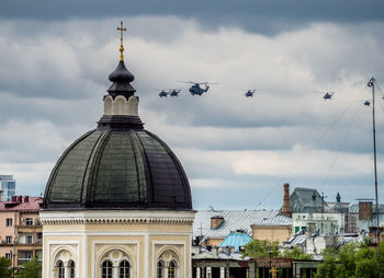 Military helicopters flying over buildings in city