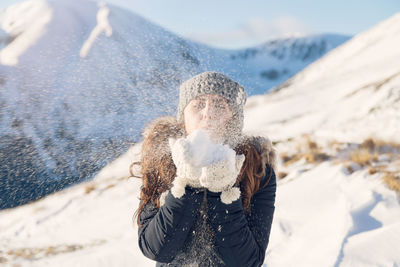 Young woman standing against snow covered tree