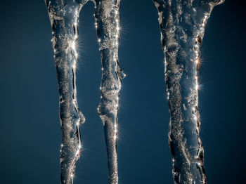 Close-up of icicles against blue sky