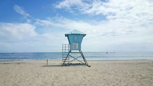 Scenic view of lookout tower on beach against cloudy sky