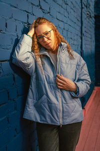 Young woman standing against wall