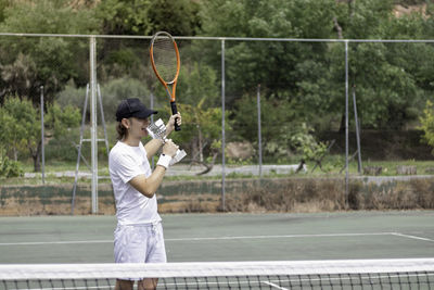 Young man winning the tennis championship biting the cup as a sign of victory wearing 