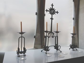 Close-up of cross on table by window at home