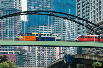 Low angle view of trains on railway bridge against buildings