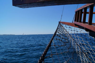 Low angle view of sailboat on sea against clear blue sky