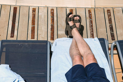 Low section of man relaxing on lounge chair during sunny day