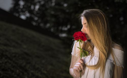 Close-up of woman holding rose against blurred background