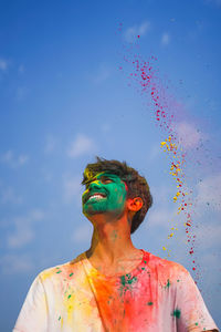 Low angle view of man playing holi against sky