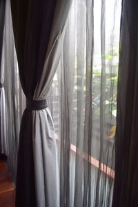 White curtain hanging on glass window at home