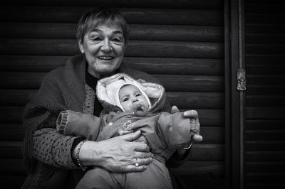 Smiling grandmother with baby against wall