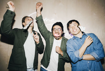 Carefree multiracial male friends with props enjoying in college dorm