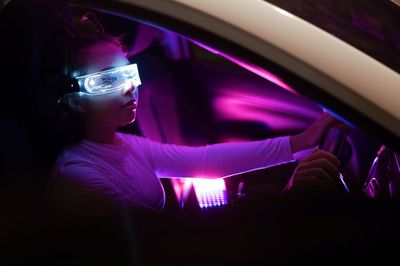 Portrait of young woman standing in car