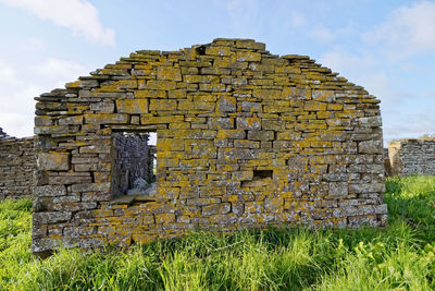 Stone wall on field against sky