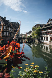 Scenic view of river by buildings against sky