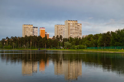 Reflection of trees and buildings in lake against sky