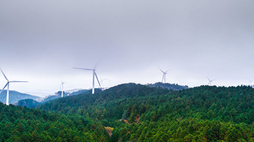 Wind turbines on field against sky