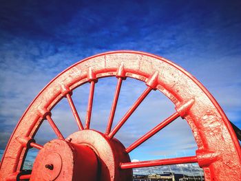 Low angle view of old wheel against sky