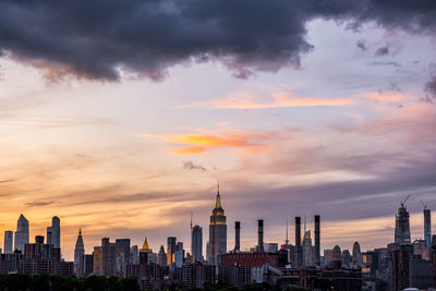 Buildings in city against cloudy sky during sunset